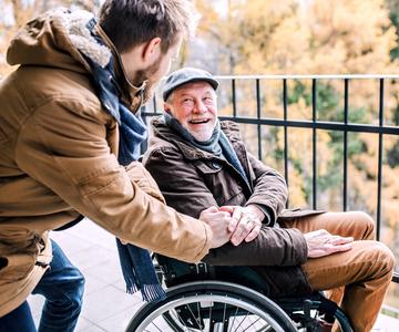 Older adult in a wheelchair smiling at a family member.