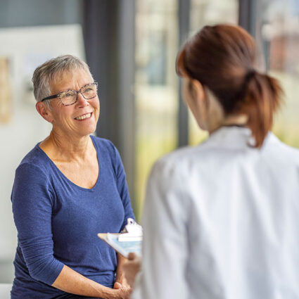 Patient in an exam room smiling at her physician.