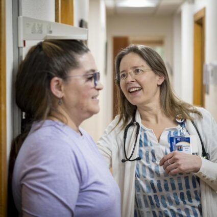 A patient stands to get her height measures by a clinician.