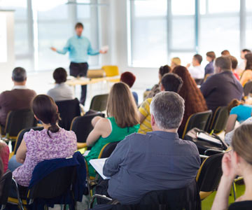 A group of people listening to a speaker in a classroom.
