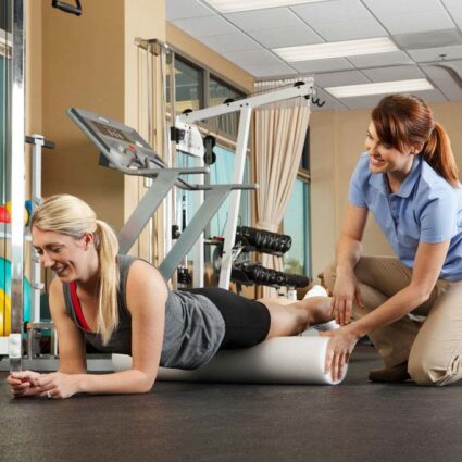 Physical therapist working with a patient using a foam roller.