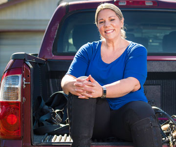 Amie smiling as she sits on the tailgate of her truck.