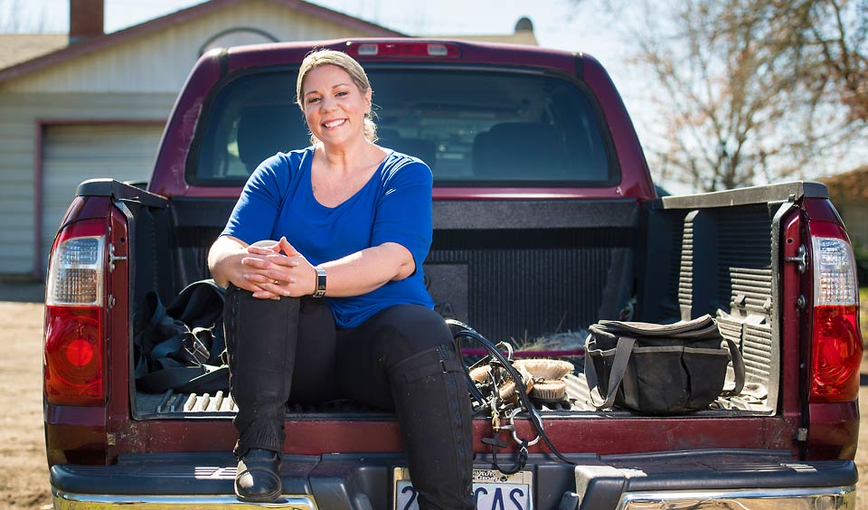 Amie smiling as she sits on the tailgate of her truck.