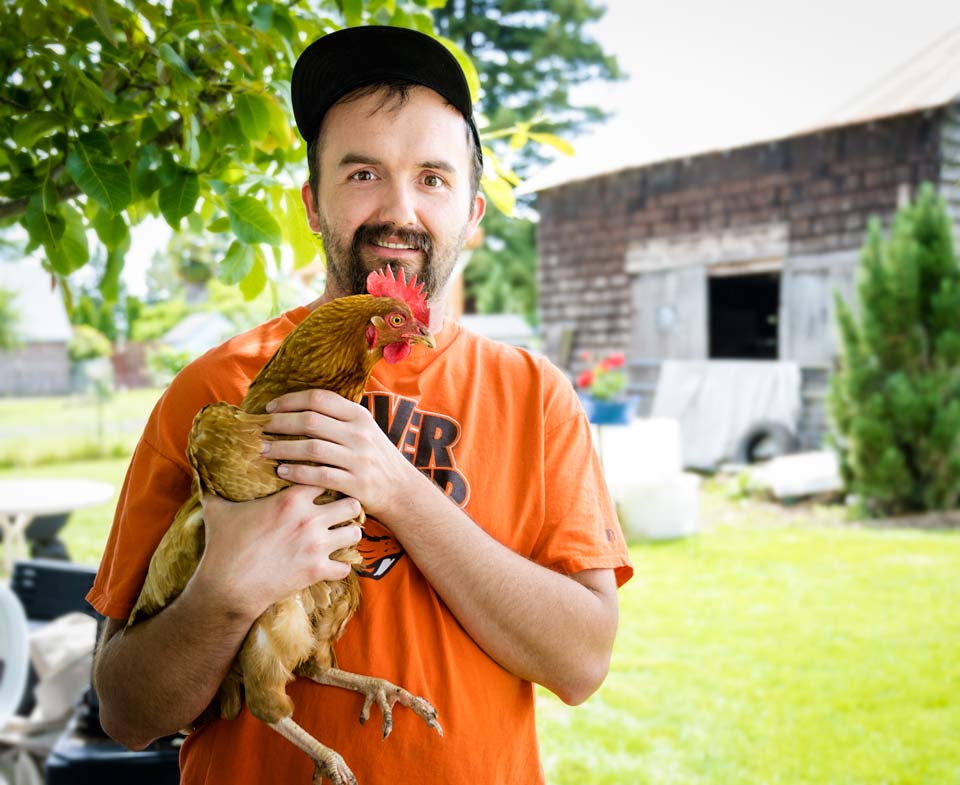 A smiling Anthony holding a chicken.
