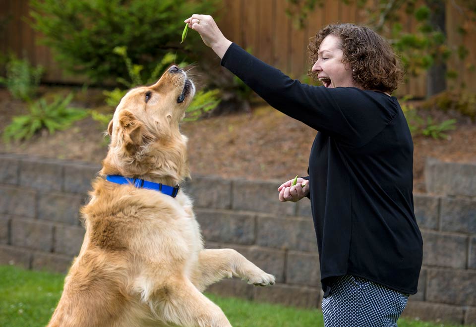 An amused Audrey getting her dog to perform tricks for fresh peas.