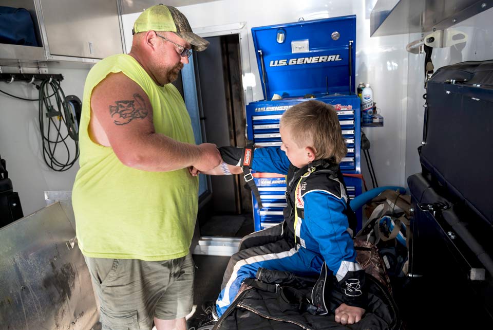 Brody's dad helps him with his gear before a race.