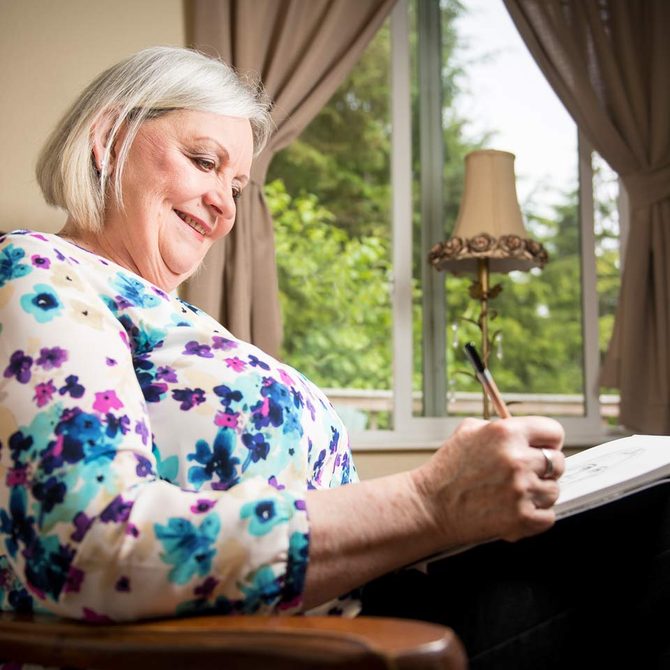Donni looking contented while sketching on a pad in her lap.
