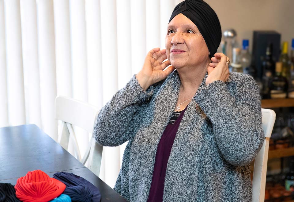 Maria trying on a cap from the cancer resource center.