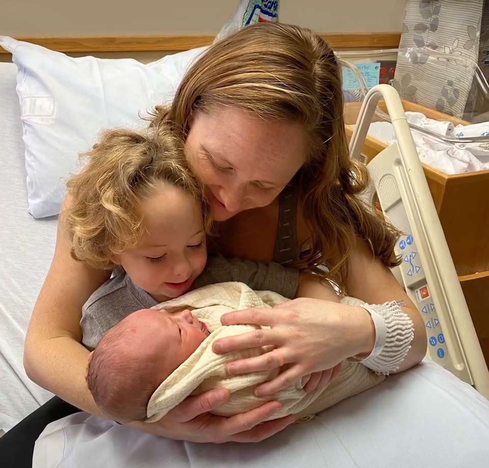 Morgan holds her young son and newborn after the delivery of her youngest child.