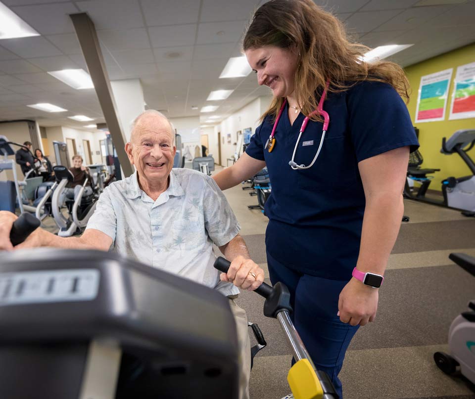 Tom working out at the cardiac rehabilitation gym in Newport, talks with one of the rehabilitation specialists.