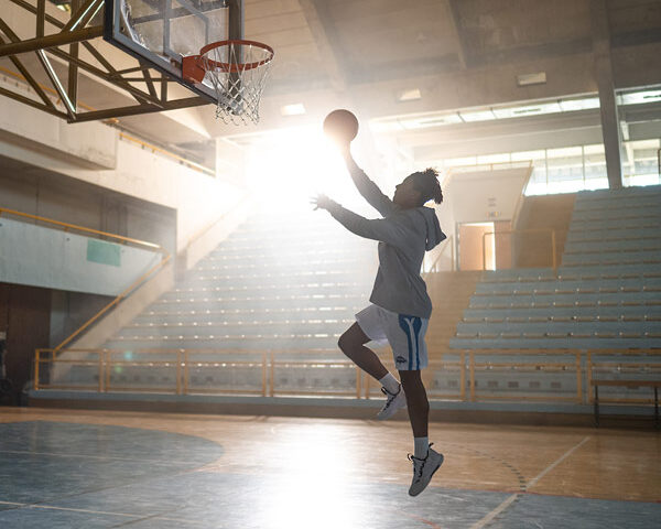 A silhouetted basketball player making a lay up.