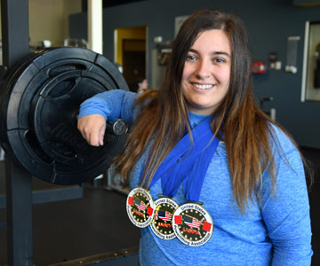 Ryleigh standing at SamFit wearing her awards.