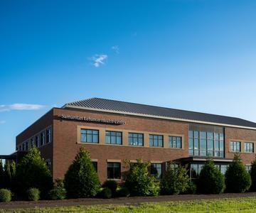 A brick two story building that is the Samaritan Lebanon Health Center. There is a bright blue sky in the background.