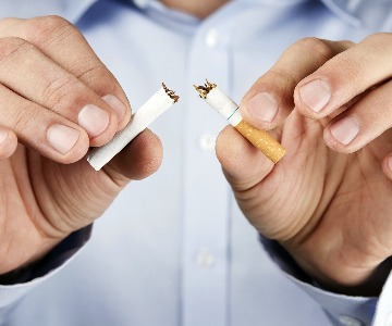 Male hands holding out a broken cigarette with one half in each hand between his fingers