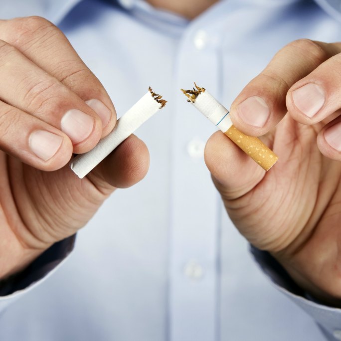 Male hands breaking a cigarette in half.