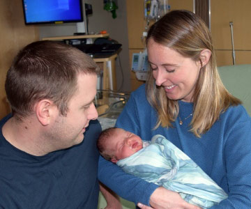Local Newport couple smiling at their new born.