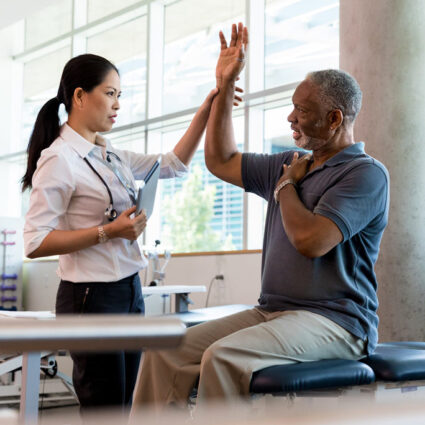 A primary care sport medicine physician checks her patient's range of motion for a shoulder injury.