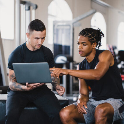 A sports physical therapist consulting with a client at a gym.
