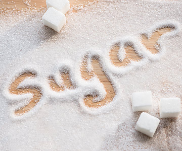 "Sugar" written out on a pile of white cane sugar.