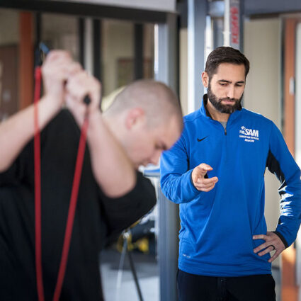 SAM trainer with a client in the gym using bands for strength training.