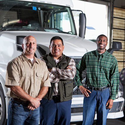 Three truck drivers standing in front of a white semi truck.