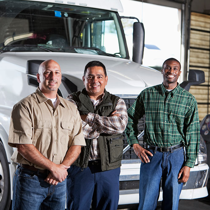 Three truck drivers standing in front of a white semi truck.