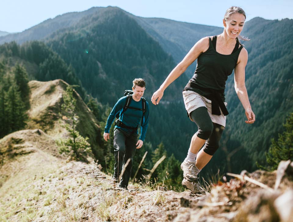 Woman and man hiking over rugged terrain.