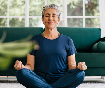 Smiling woman meditating from the comforts of her home.