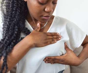 Woman does self screening for breast cancer, with hand over shirt